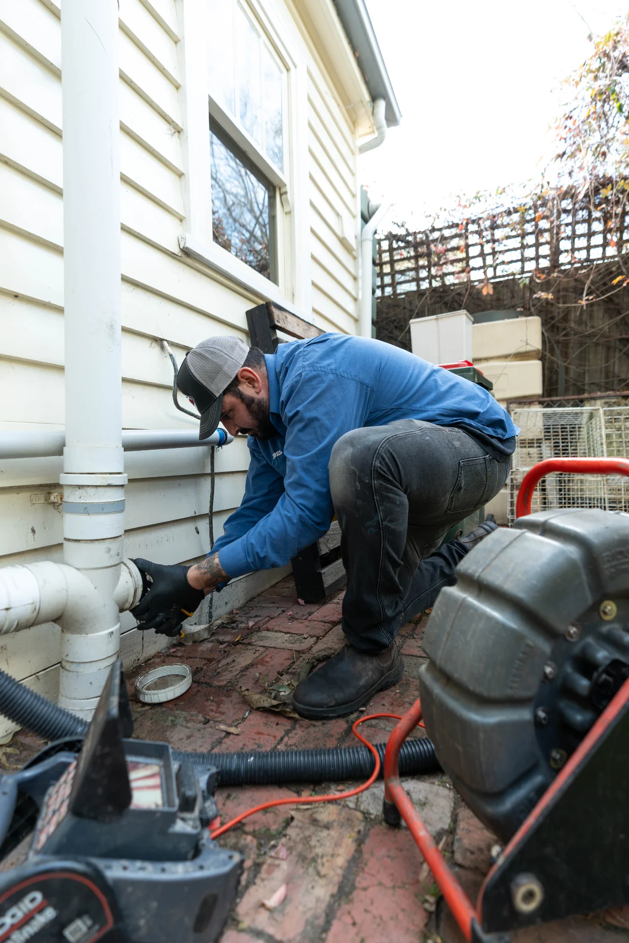 Roof plumber clearing a blocked downpipe so roof water drains away properly