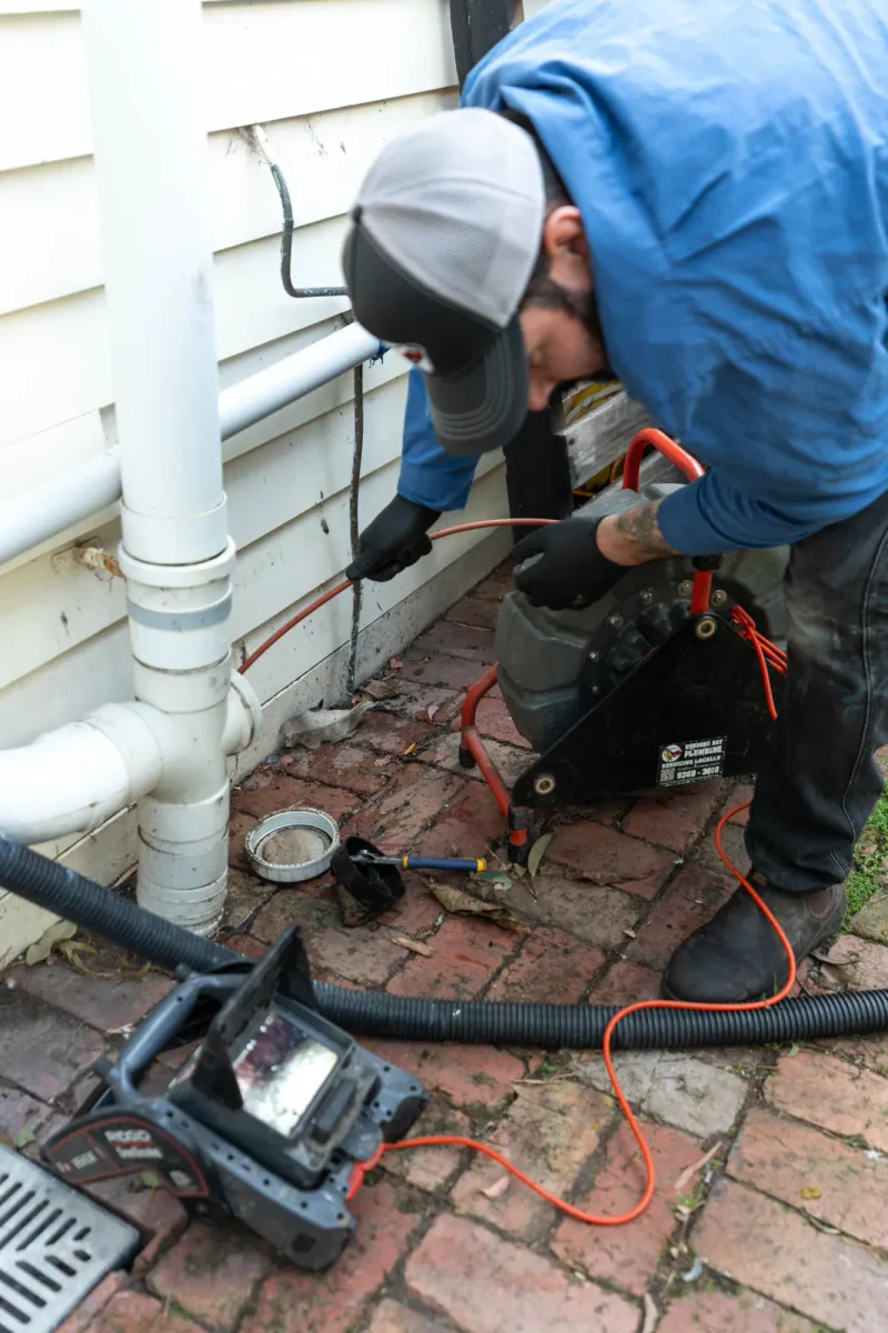 Drain clearing machine in use on a paved driveway in Yarraville