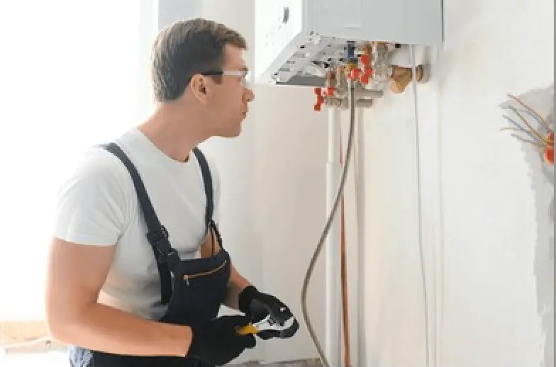 Gas fitter carrying out a safety check on a wall-mounted gas hot water unit